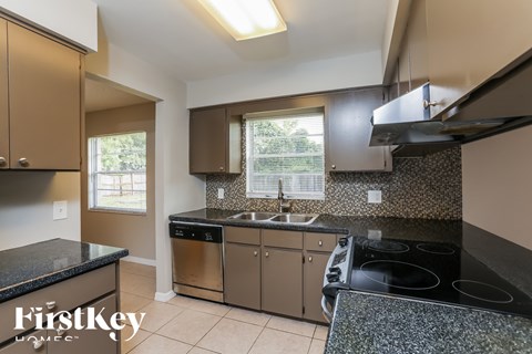 A kitchen with a black granite countertop and a stove top oven.