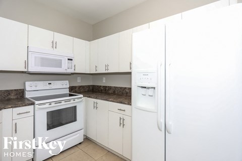A kitchen with white appliances and cabinets.