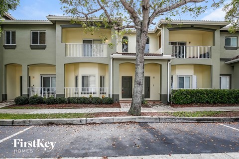 an apartment building with a sidewalk and trees in front of it