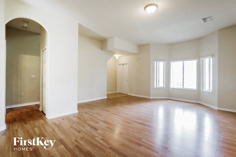 an empty living room with wood floors and white walls