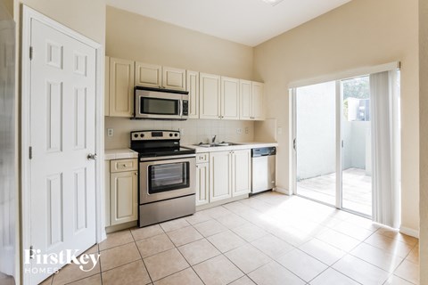 a kitchen with white cabinets and appliances and a sliding glass door