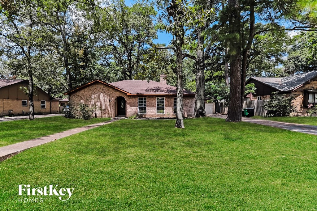 A grassy area with a house and trees in the background.