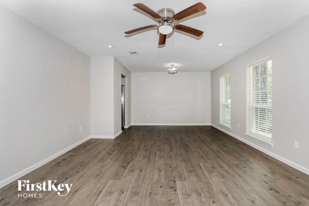A spacious room with a ceiling fan and wooden flooring.