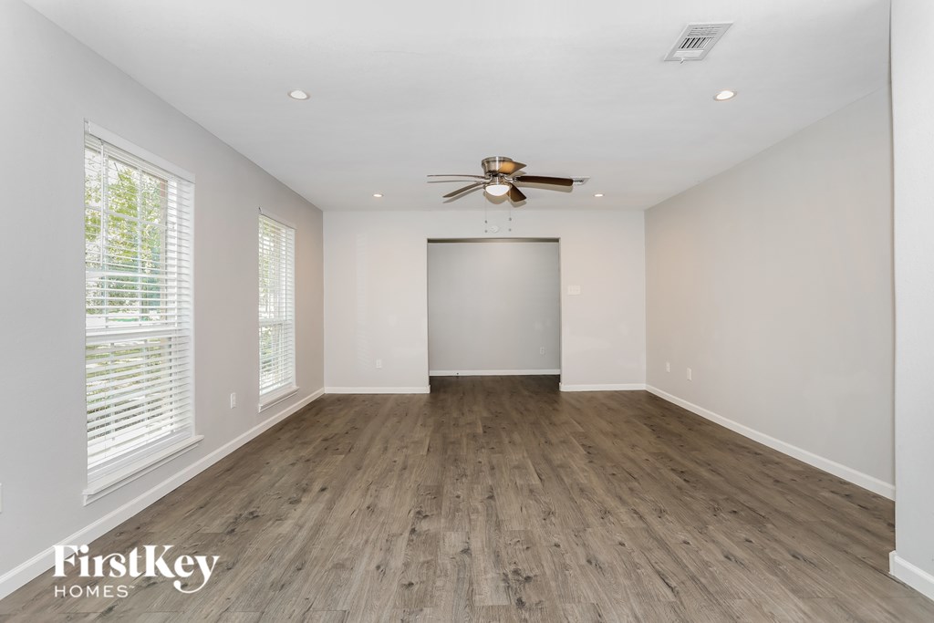 A spacious room with wooden flooring and a ceiling fan.