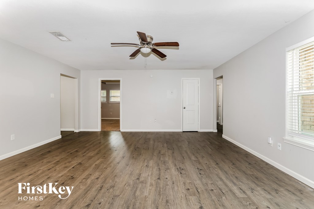 A spacious room with a ceiling fan and wooden flooring.
