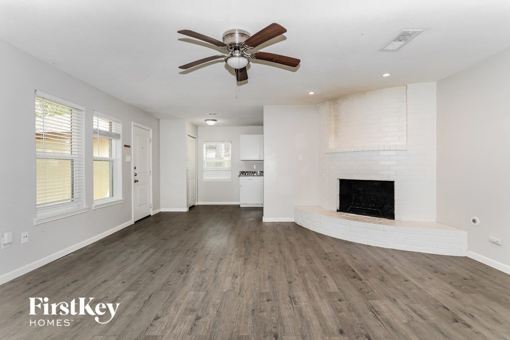 A spacious living room with a fireplace and a ceiling fan.