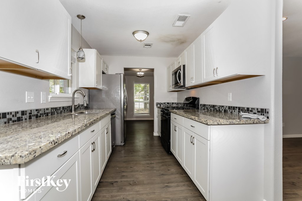 A kitchen with white cabinets and a granite countertop.