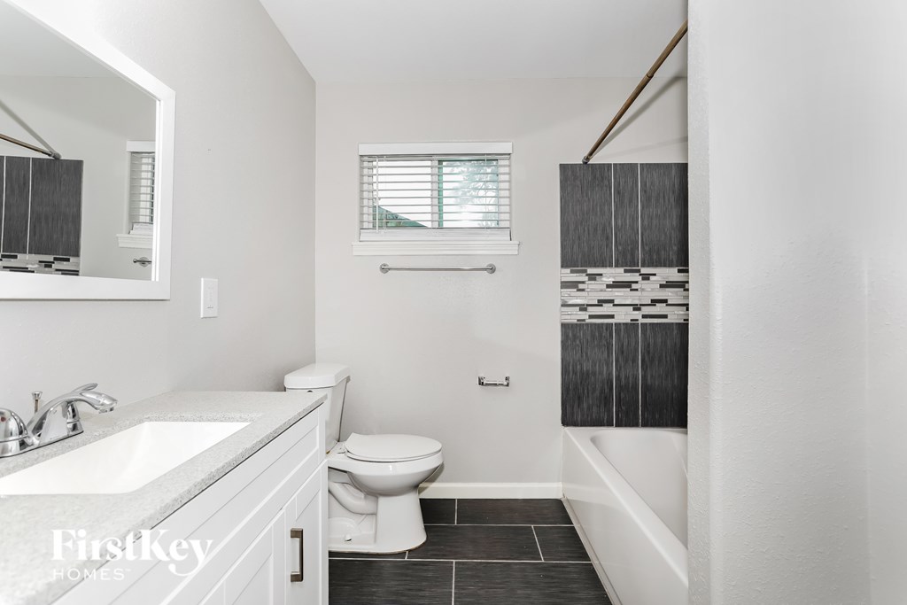 A white bathroom with a toilet, sink, and a mirror.