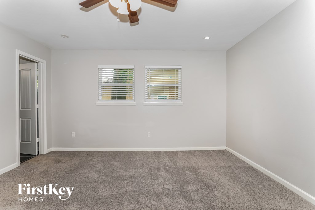 A room with a carpeted floor and a ceiling fan.