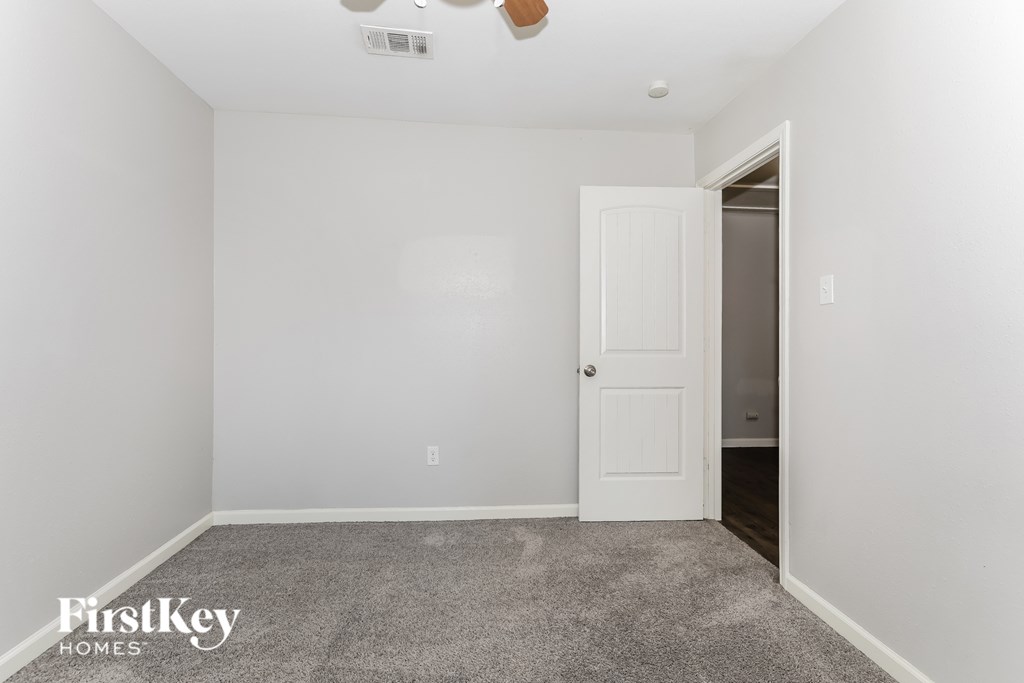 A room with a white door and a fan on the ceiling.