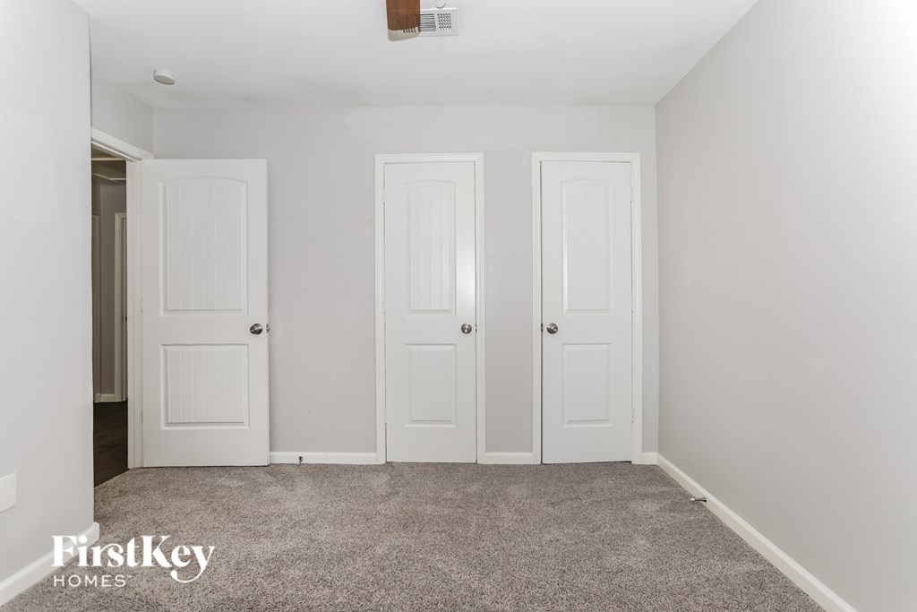 Three white doors in a room with a carpeted floor.