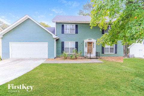 a blue house with a lawn and a white garage door