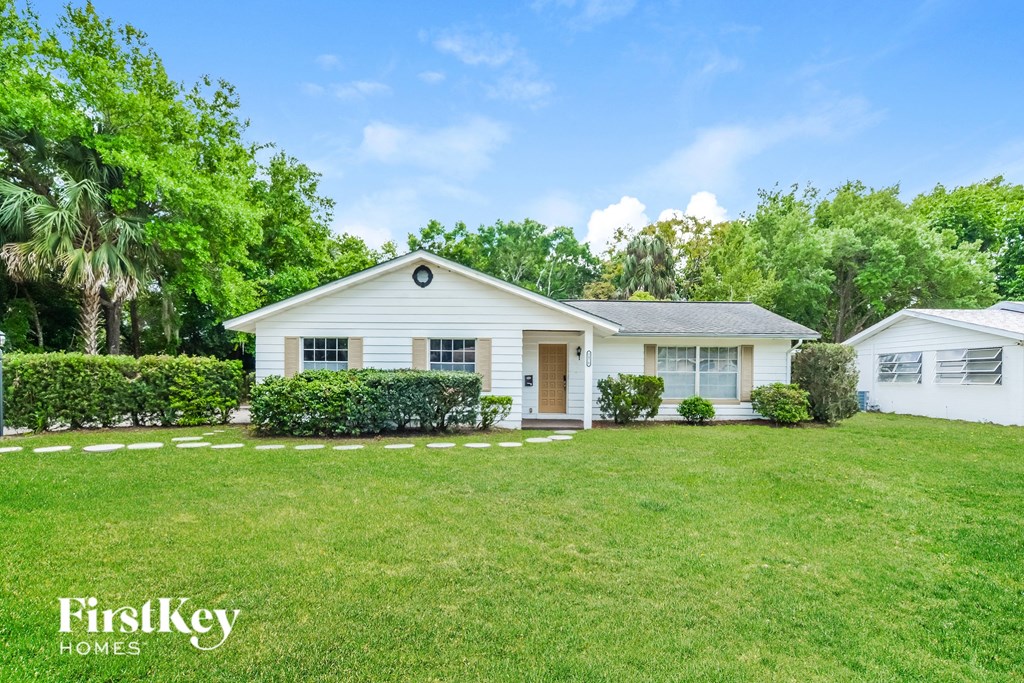 a white house with a green lawn and trees
