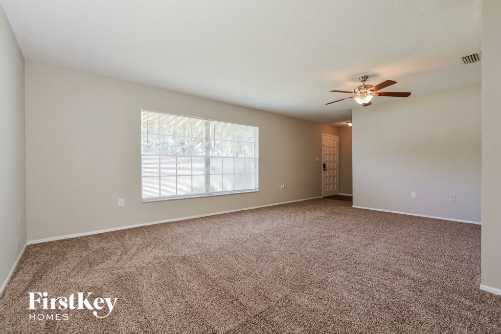 an empty living room with carpet and a ceiling fan