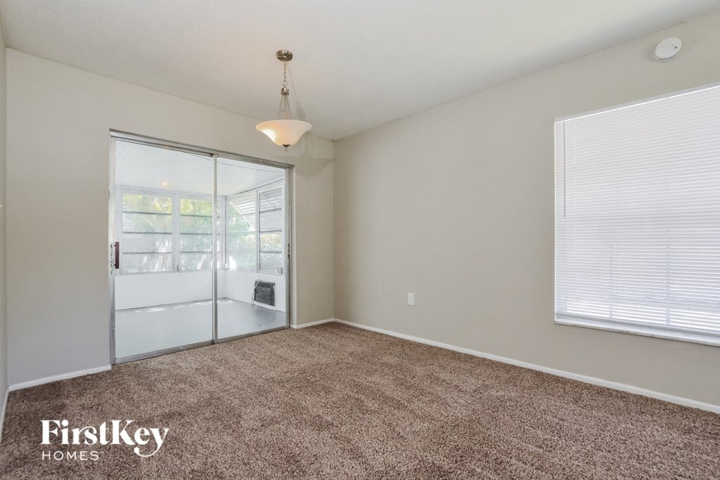 an empty living room with a window and a door to a kitchen