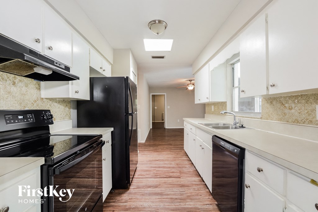 a kitchen with white cabinets and black appliances