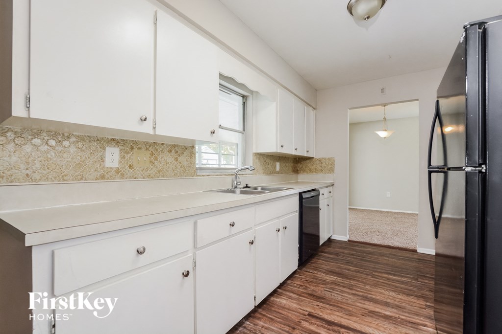 a white kitchen with white cabinets and a black refrigerator