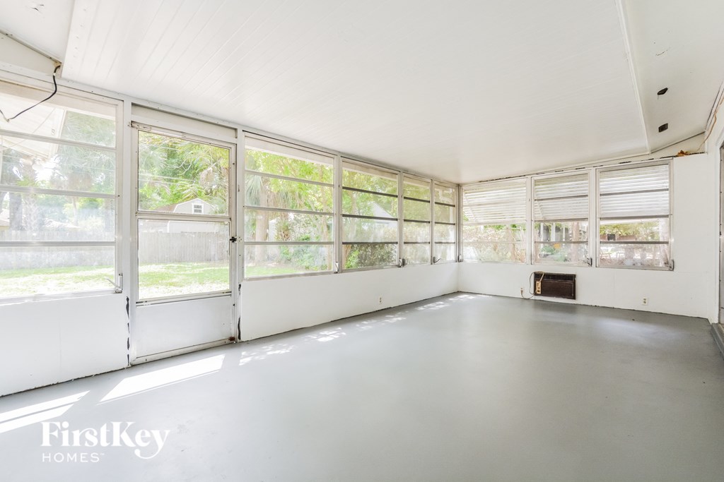 an empty room with large windows and a white floor