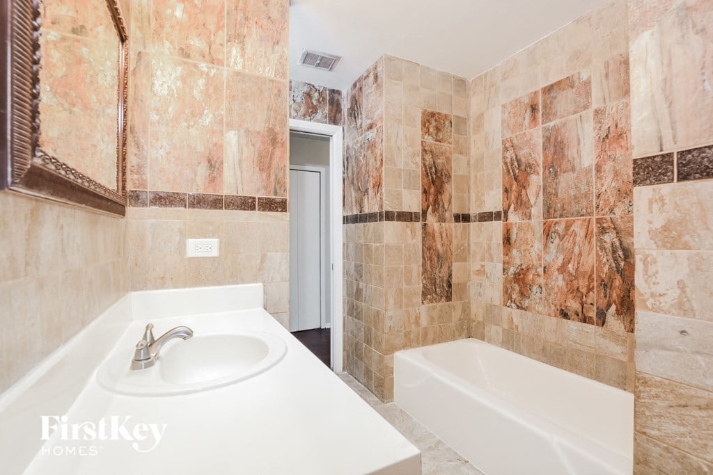 a tiled bathroom with a sink and a tub