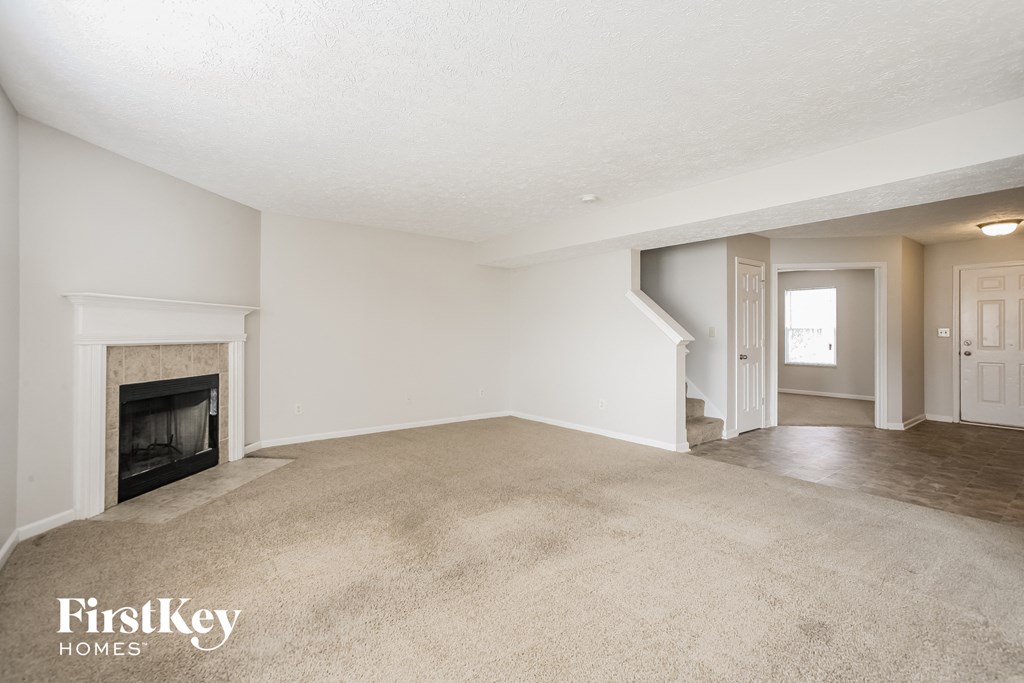 A spacious living room with a fireplace and a carpeted floor.