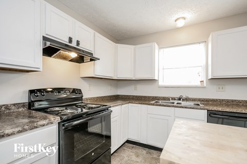 A kitchen with white cabinets and a black stove top oven.