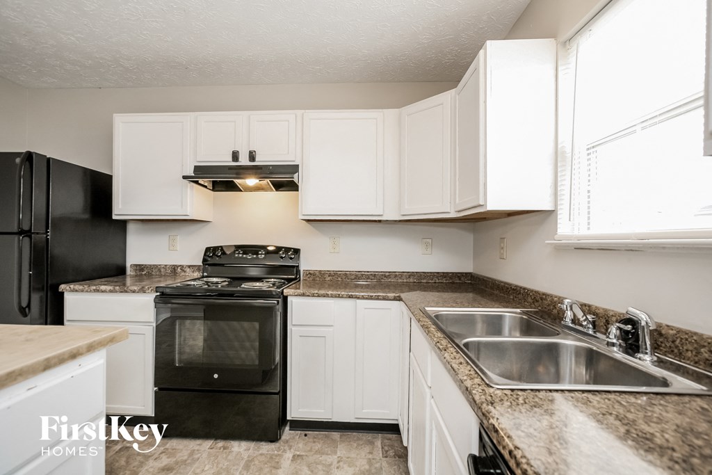 A kitchen with black appliances and white cabinets.