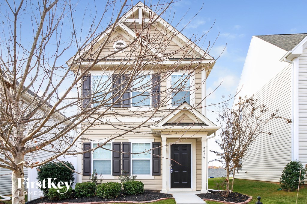 A house with a black door and a sign that says "FirstKey" in front of it.