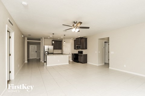A spacious living room with a kitchen in the background.