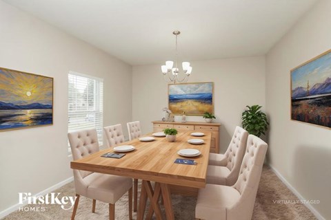 A dining room with a wooden table and chairs, a chandelier, and two paintings on the wall.