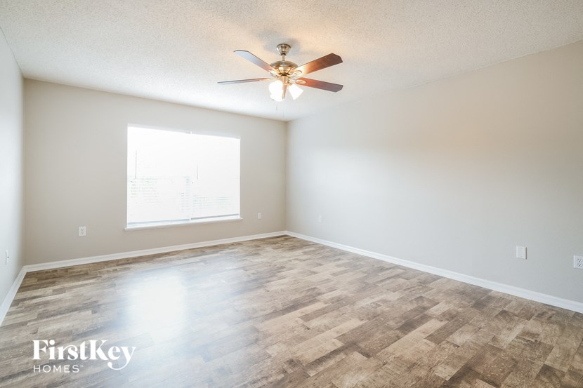 the spacious living room with wood flooring and a ceiling fan