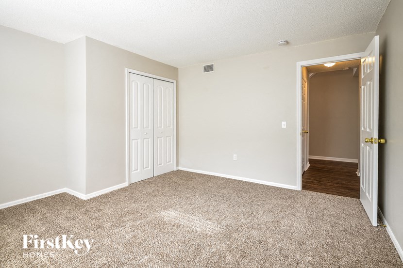 a bedroom with a carpeted floor and a door to a hallway
