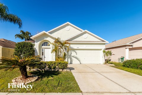 a house with a driveway and palm trees in front of it