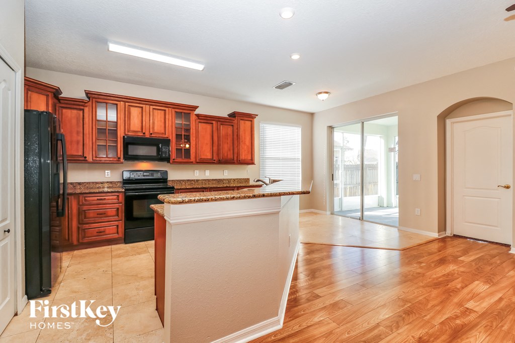 a kitchen with wood flooring and a large island with black appliances