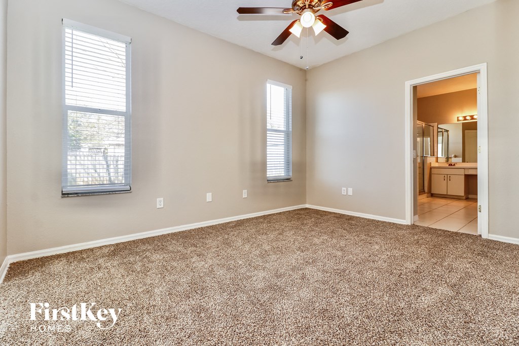an empty living room with a ceiling fan and a carpet