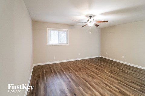 the spacious living room with hardwood flooring and a ceiling fan