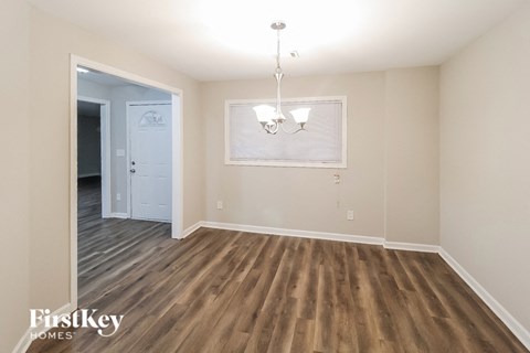 an empty living room with wood flooring and a door to a hallway