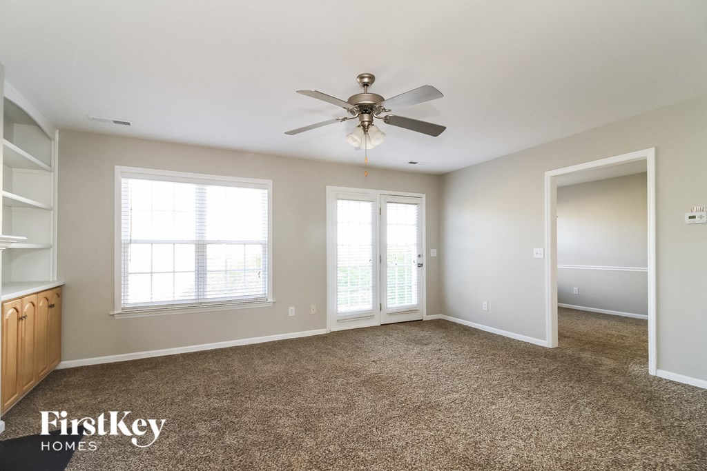 a living room with carpet and a ceiling fan