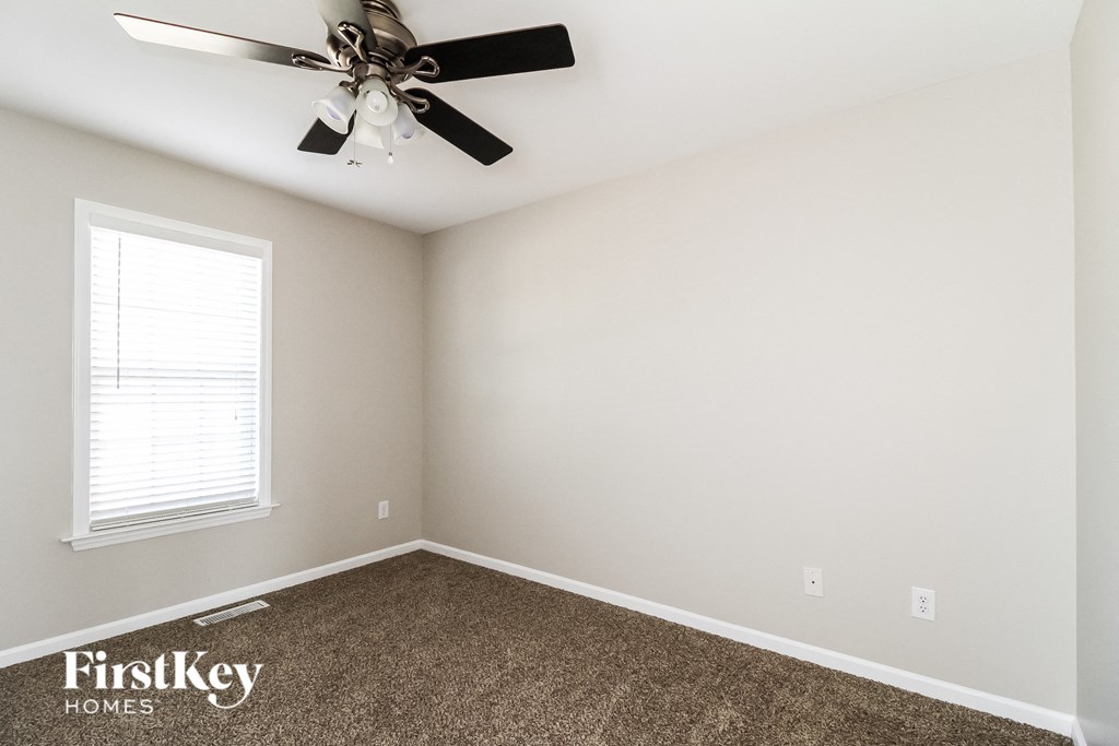 a bedroom with a ceiling fan and carpet