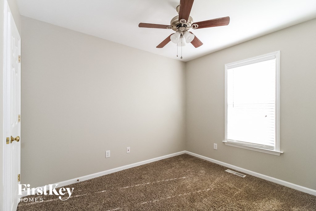 a bedroom with a ceiling fan and a carpet