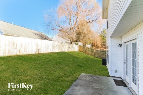 a backyard with green grass and a fence and a driveway