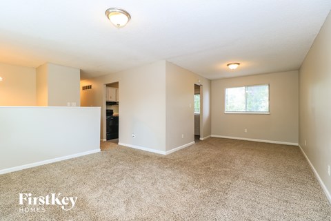 A spacious room with a carpeted floor and a window.