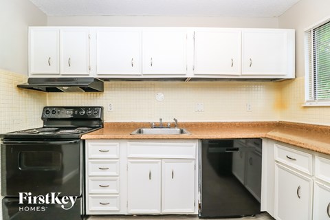 A kitchen with white cabinets and a black stove top oven.