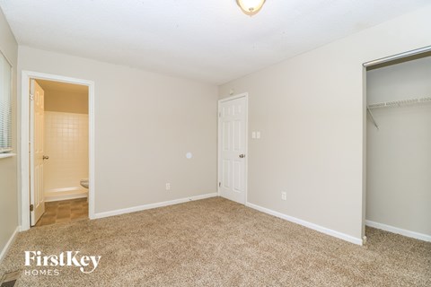 A bedroom with a carpeted floor and a closet.