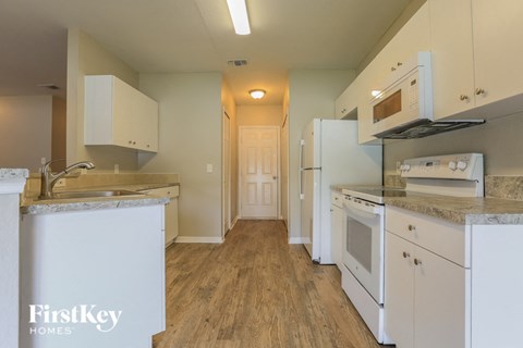 A kitchen with white cabinets and a wooden floor.
