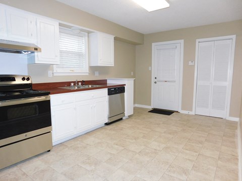 A kitchen with white cabinets and a tile floor.