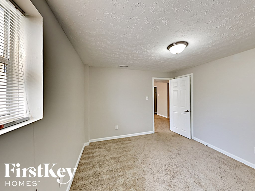 an empty living room with a white door and a window