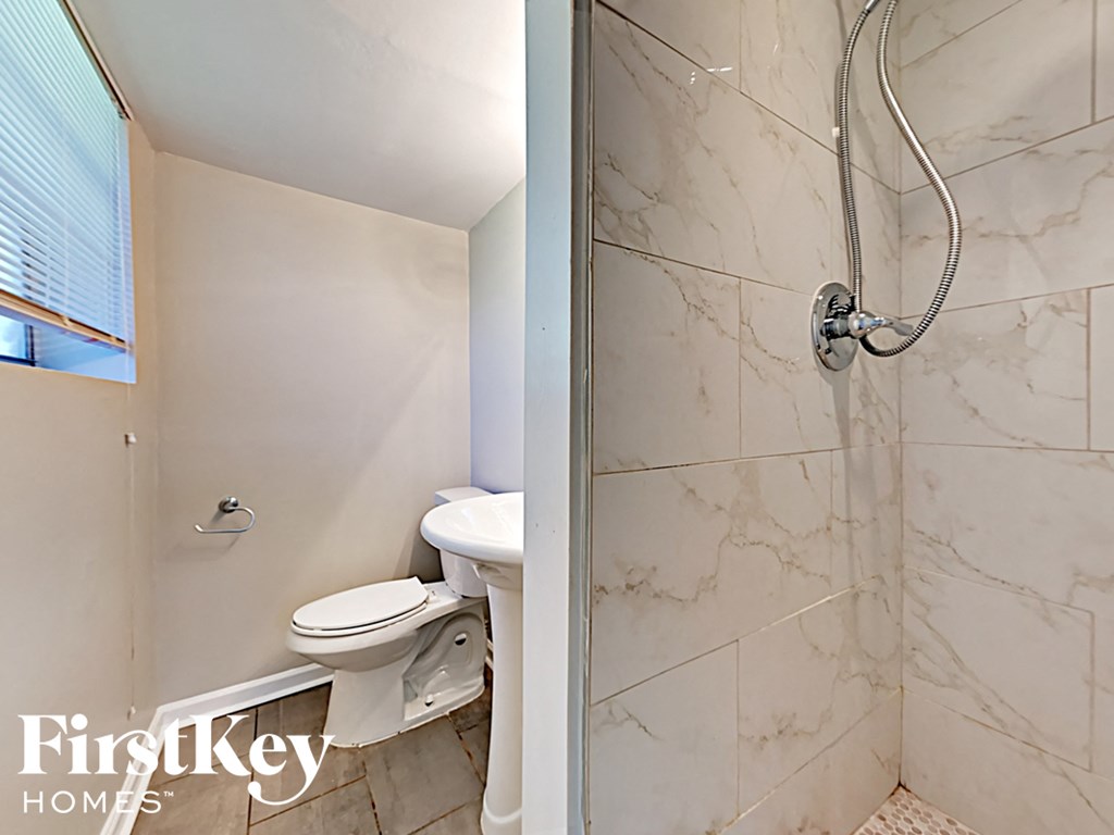 a white bathroom with a toilet and a shower