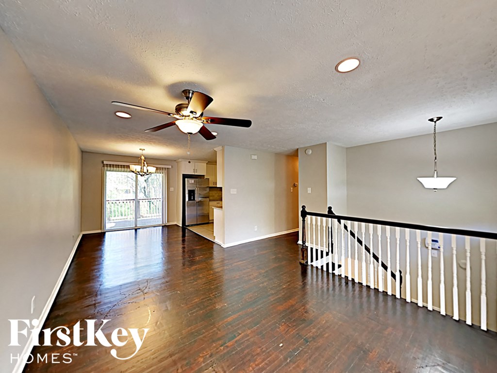 an empty living room with wood floors and a ceiling fan