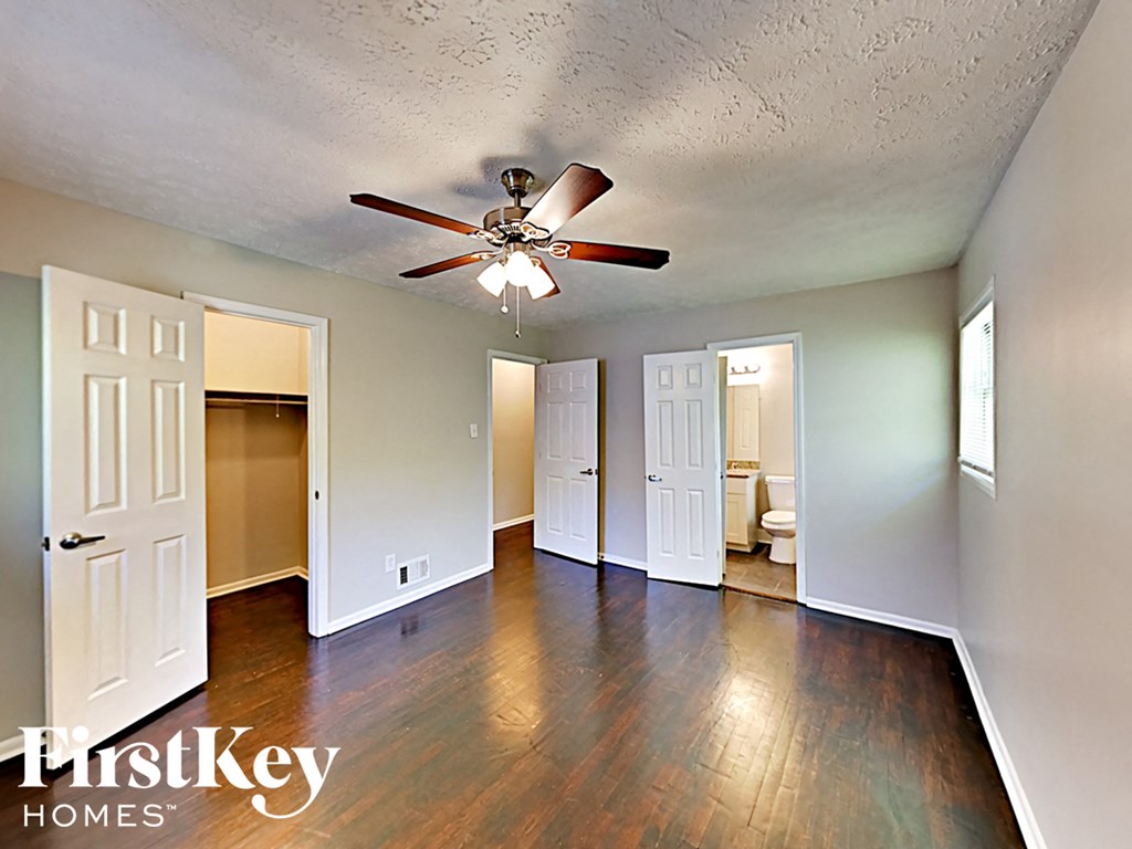 an empty living room with wood floors and a ceiling fan