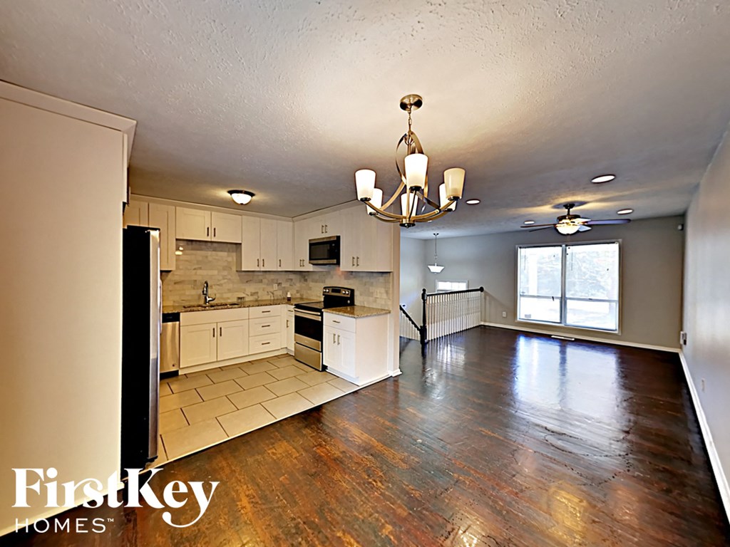 the kitchen and living room of an empty house with a chandelier
